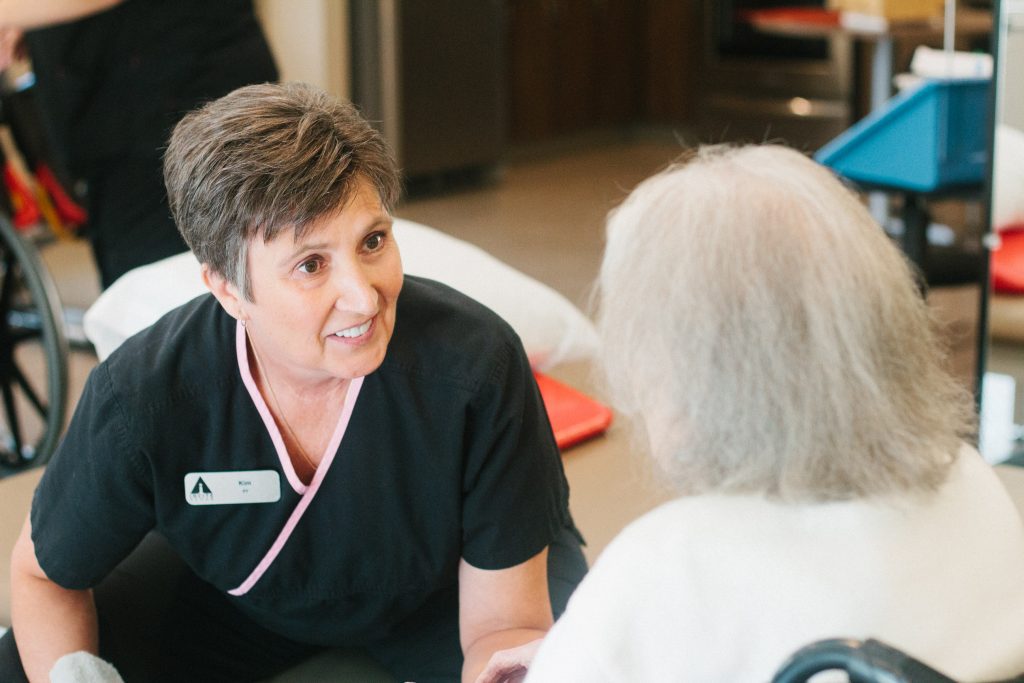 A woman smiles at a nurse at a skilled nursing facility nursing home