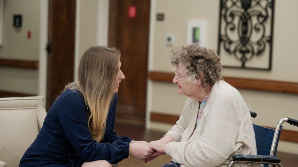 A woman smiles at a nurse in a long term care facility