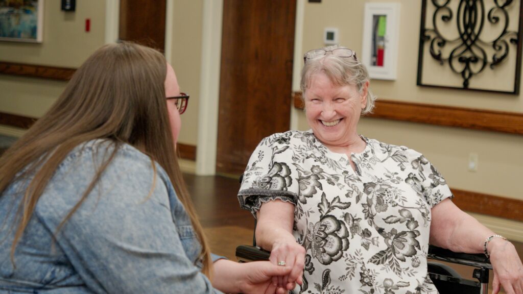 A woman smiles at a nurse at a respite care facility