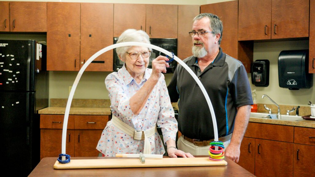 A woman in short term rehab physical therapy being assisted by a nurse